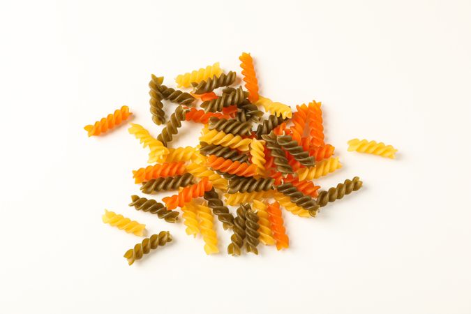 Color pasta on blank background, space for text. Dry uncooked whole pasta
