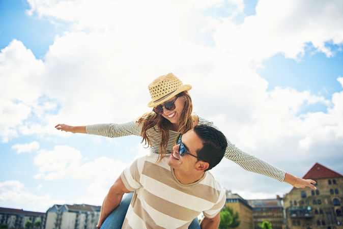 Woman on man’s back with outstretched arms