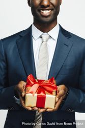 Image of cropped Black man holding present wrapped in gold paper and red bow beGnP5