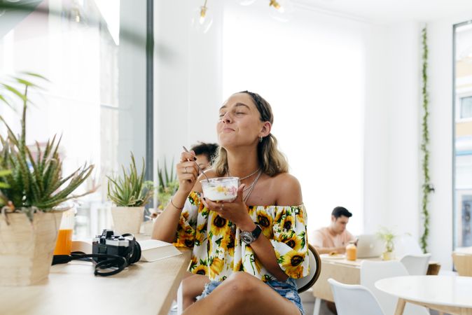 Stylish woman eating and reading book in cafe