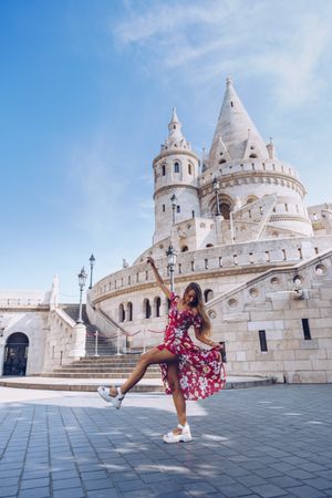 Laughing women in colorful dress dancing against old building
