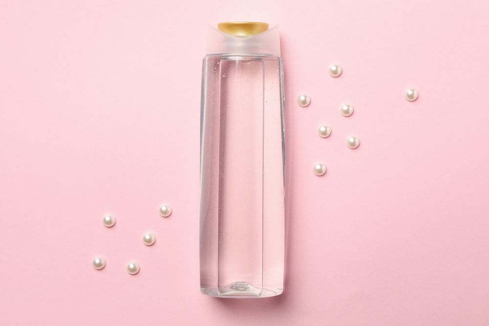 Blank shampoo bottle on pink background, space for text