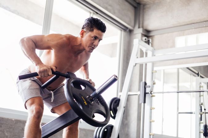 Muscular man working out with weight machine