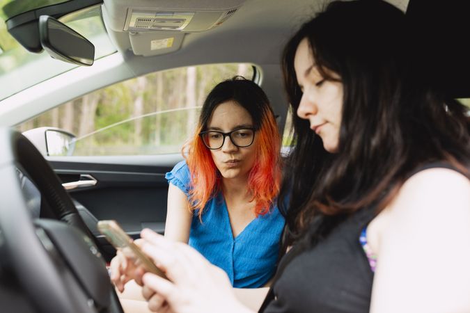 Two young women, consult the smartphone during a car trip, to check the proper route