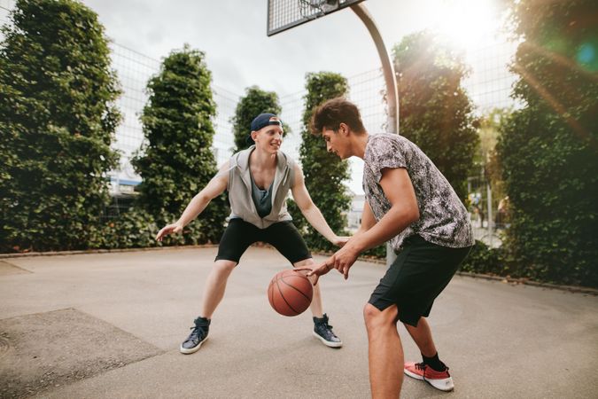 Young male friends playing basketball on outdoor court
