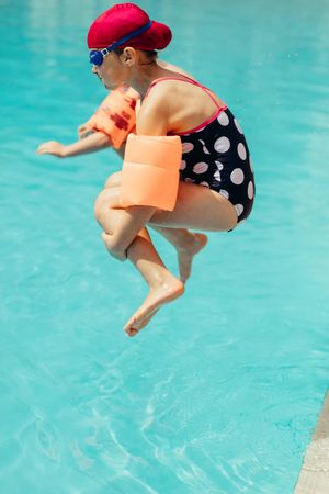 Young girl jumping into a swimming pool