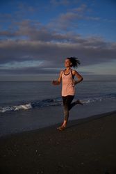 Positive Hispanic woman running along sea
