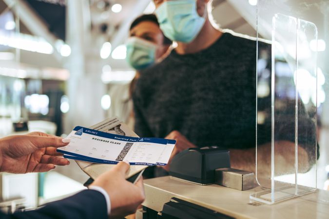 Airlines staff assisting masked man during pandemic at check-in counter