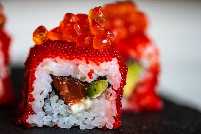 Close up of sushi rolls with roe, avocado and salmon with copy space