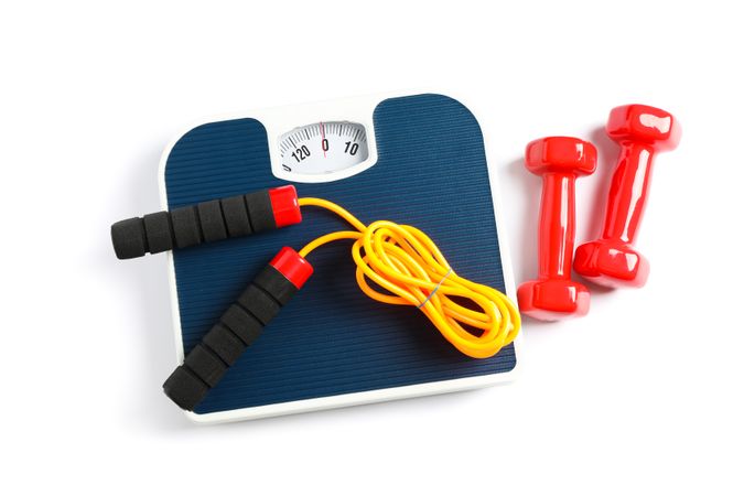 Weigh scales, skipping rope and dumbbells isolated on plain background