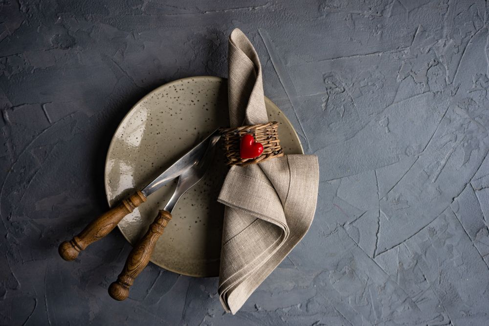 Table setting with beige ceramic plate, napkin and heart decoration