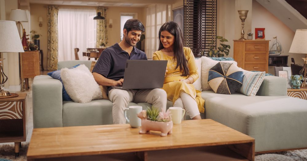 Portrait of Loving Young Indian Couple Enjoys Browsing Online Shopping Websites Together On A Laptop