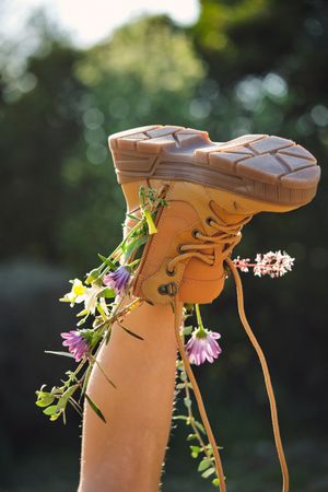 Crop person wearing boot with flowers