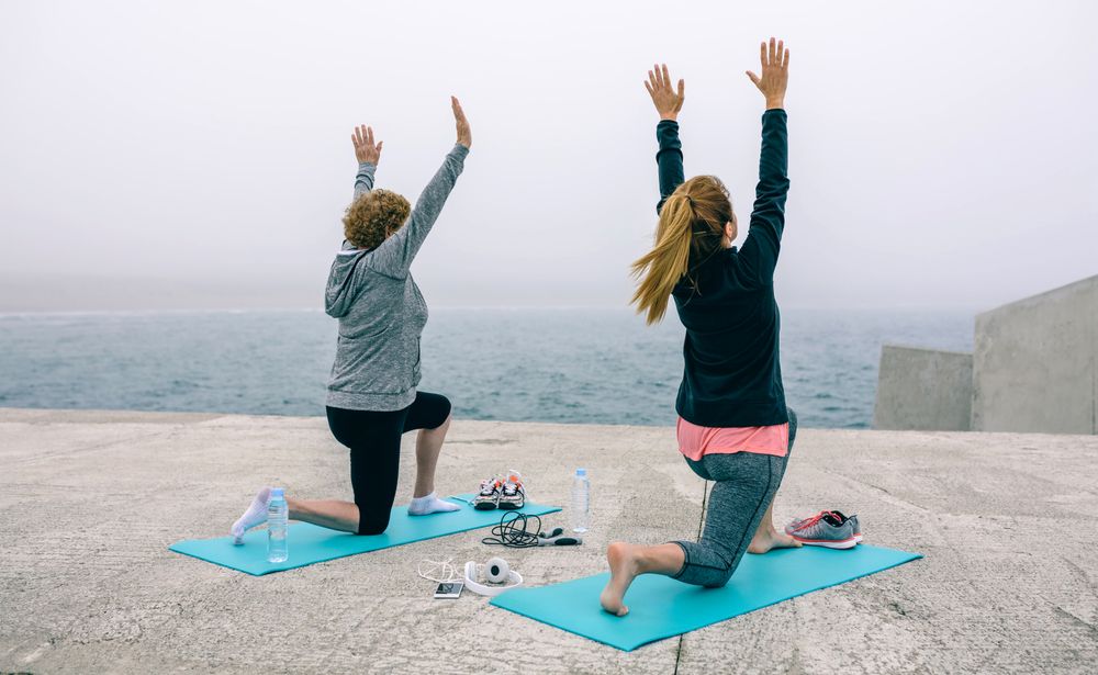 Back view of women stretching by sea pier