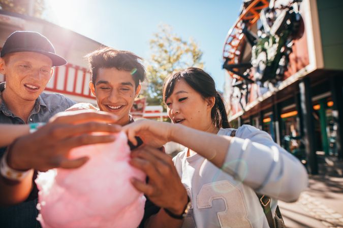 Young men and woman sharing cotton candy floss at fairground