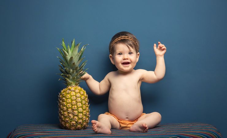 Happy baby playing with a pineapple