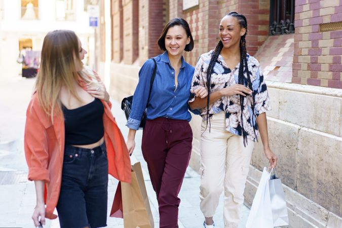 Smiling women walking down street with shopping bags