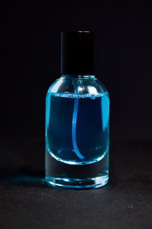 Light blue perfume bottle in dark studio with space for text