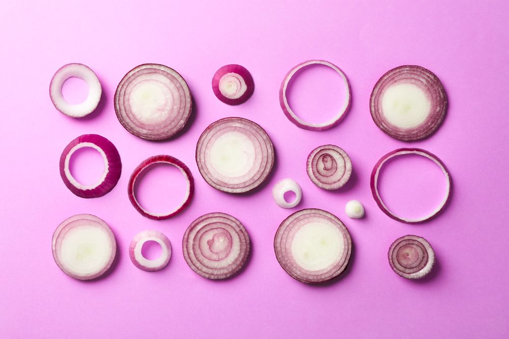 Flat lay composition with red onion rings on color background