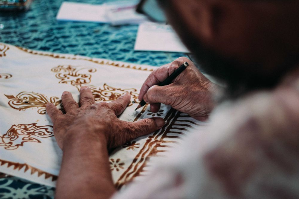 Back view of an older man drawing on textile