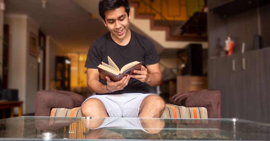 Young man reading a book in the living room
