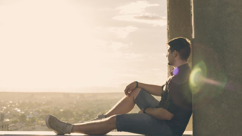 Man sitting and relaxing atop roof looking out at view