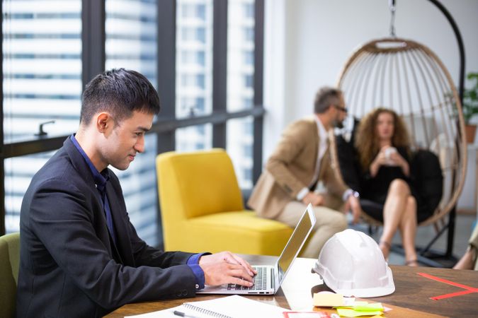 Asian businessman engineer using computer laptop at desk in busy office