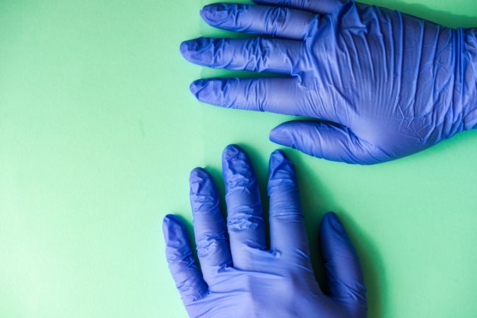 Looking down at green table with hands in blue latex gloves