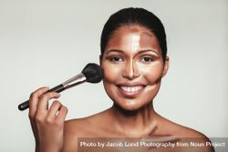 Woman applying makeup on her face with brush 5RNzr5
