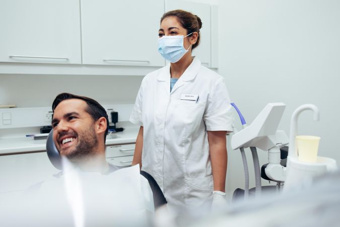 Dentist hygienist and patient looking at something and smiling