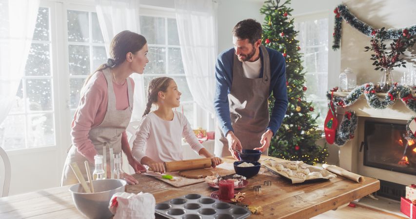 Parents and Child Baking Together During Christmas. Cute Little Girl and Parents Making Gingerbread Cookies.