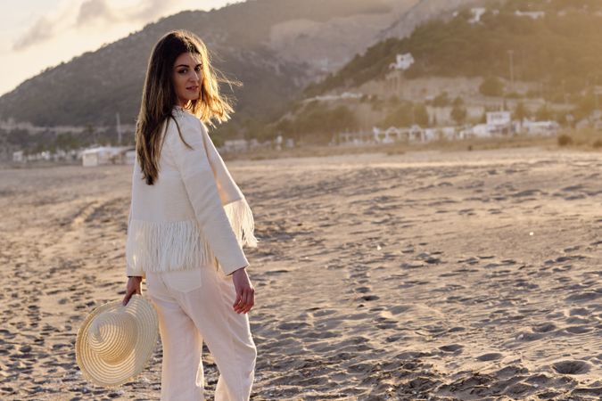A long hair fashion model with a hat at the beach at sunset in a summer day