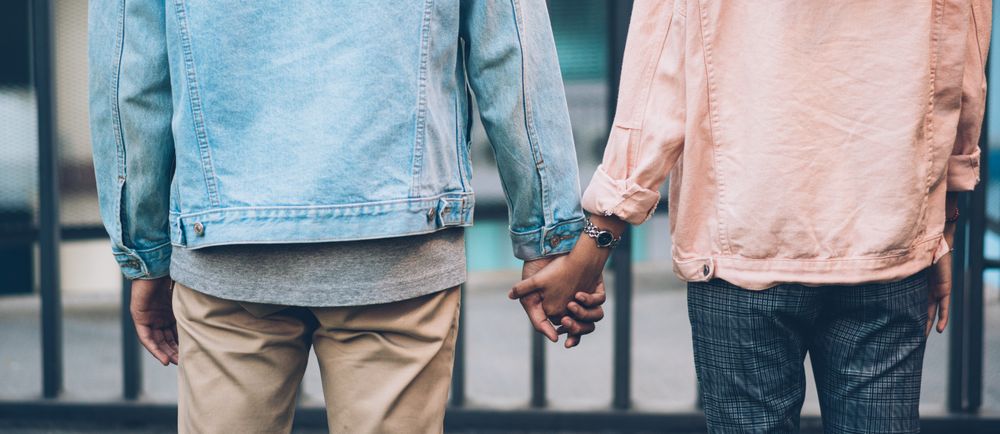Back of couple standing and holding hands together