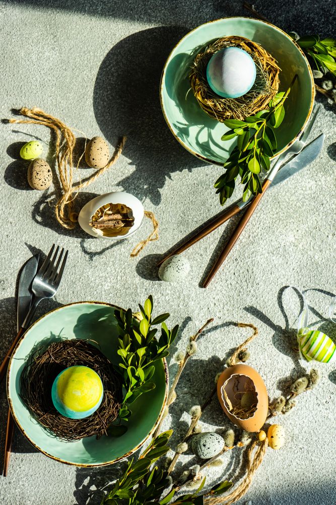 Easter table setting with blue egg in a nest in two bowls on table