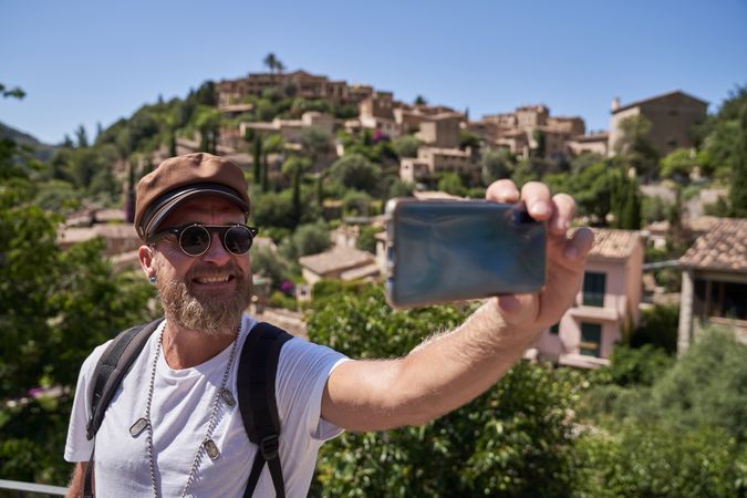 Cheerful male tourist taking selfie in old town