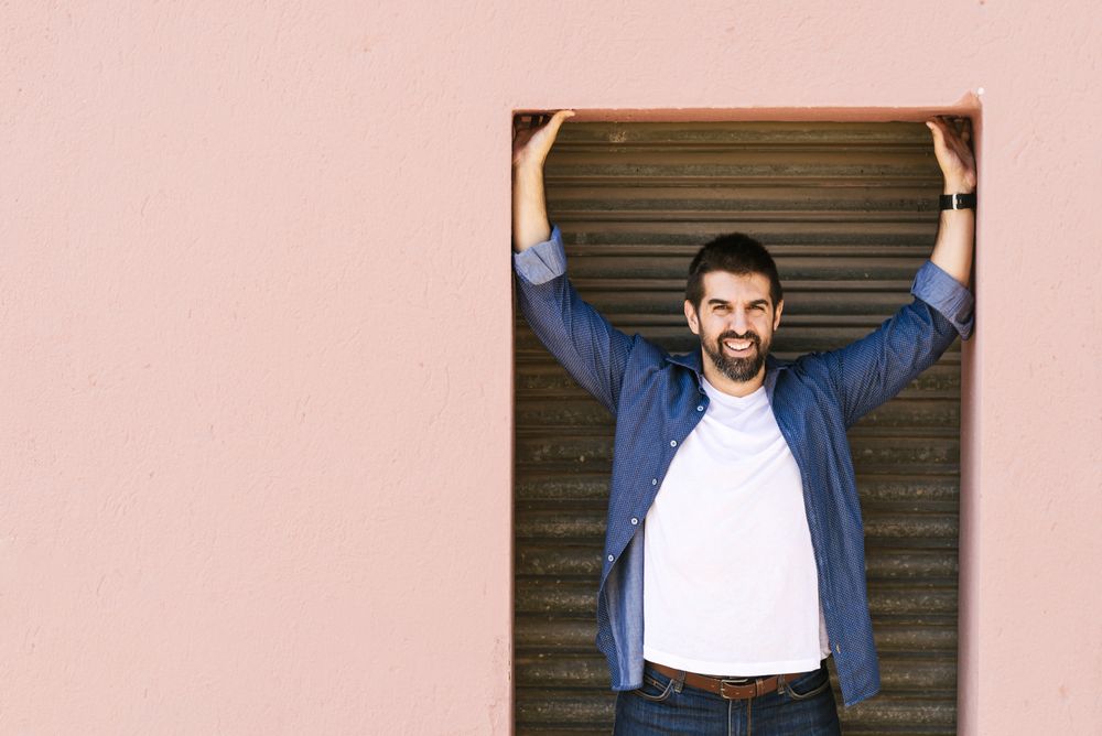 Happy man in denim in pink doorframe
