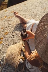 Woman relaxing and drinking beer at beach