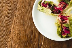 Plate with lettuce wraps on wooden table