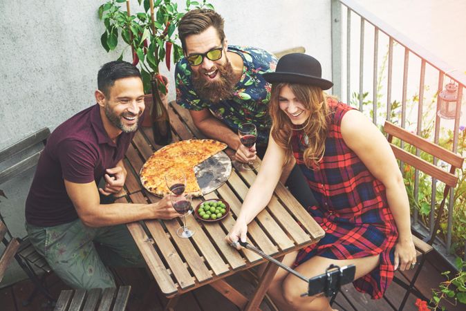 Group of people on patio with pizza, olives red wine taking a selfie