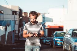 Young male walking with mobile phone