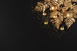 Golden holiday decorations, glitter, baubles and leaves on dark background