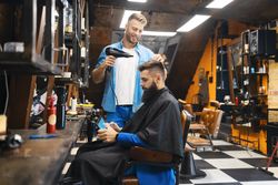 Man looking at his phone while having his hair blowdried