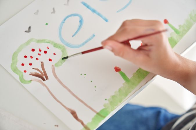 Unrecognizable kid painting tree on paper