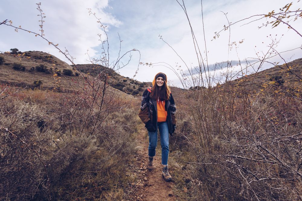 Hiker with backpack walking along pathway in autumn forest