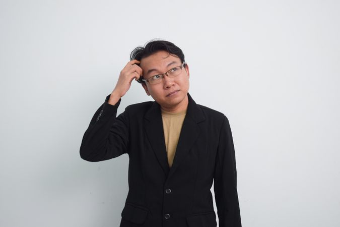 Asian businessman scratching head in studio