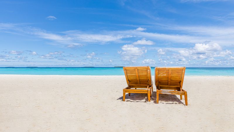 Two lounge chairs on an empty tropical beach