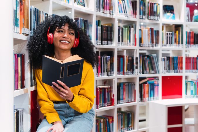 Content female student reading textbook in library