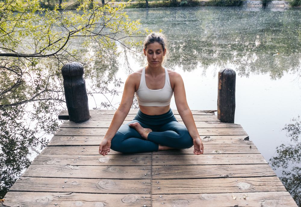 Woman meditating in nature near a lake