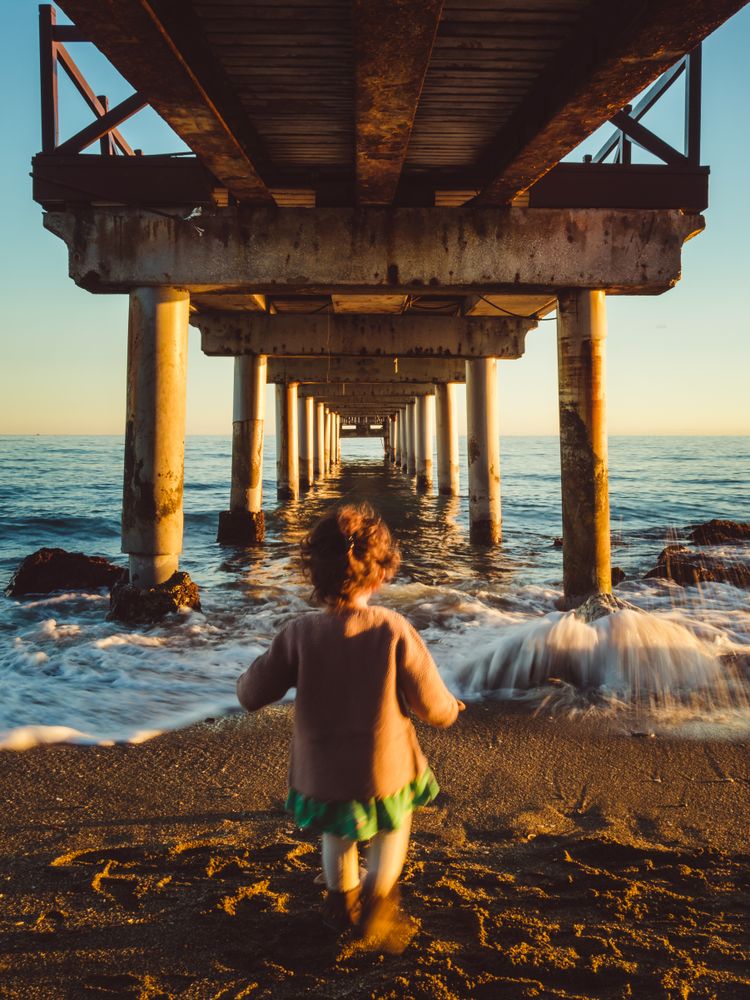 back view of kid under a pier
