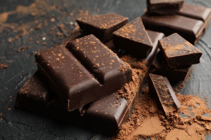 Tasty chocolate and powder on dark background